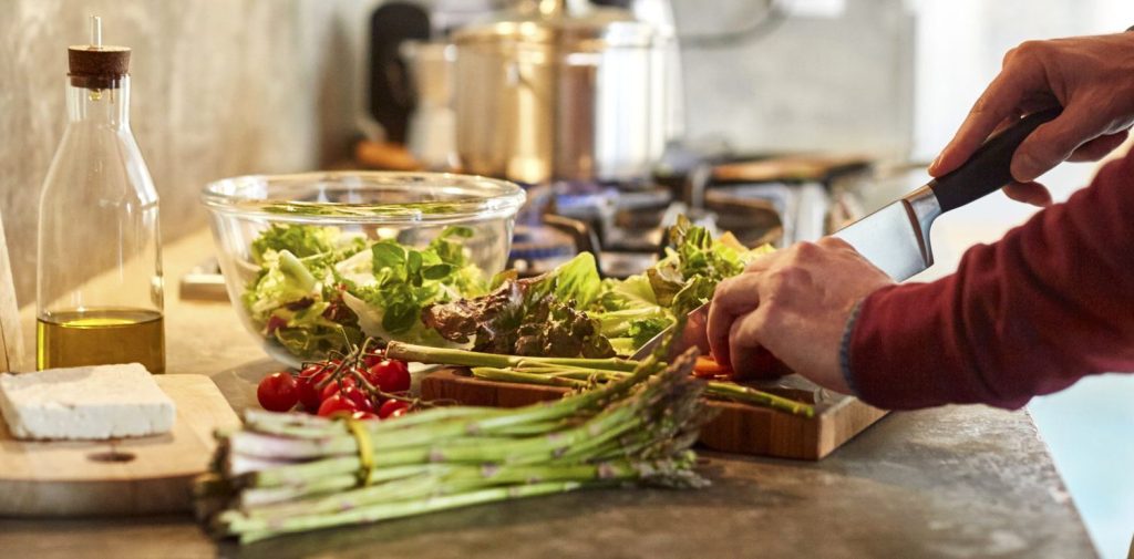 Essential kitchen tools: chopping vegetables with a chef’s knife on a cutting board.